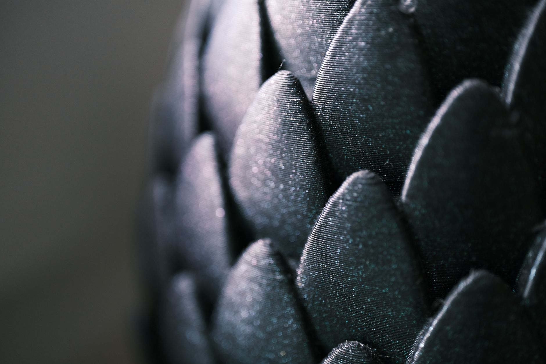 Intricate close-up of glossy black scale-like pattern with a captivating texture and shimmer.