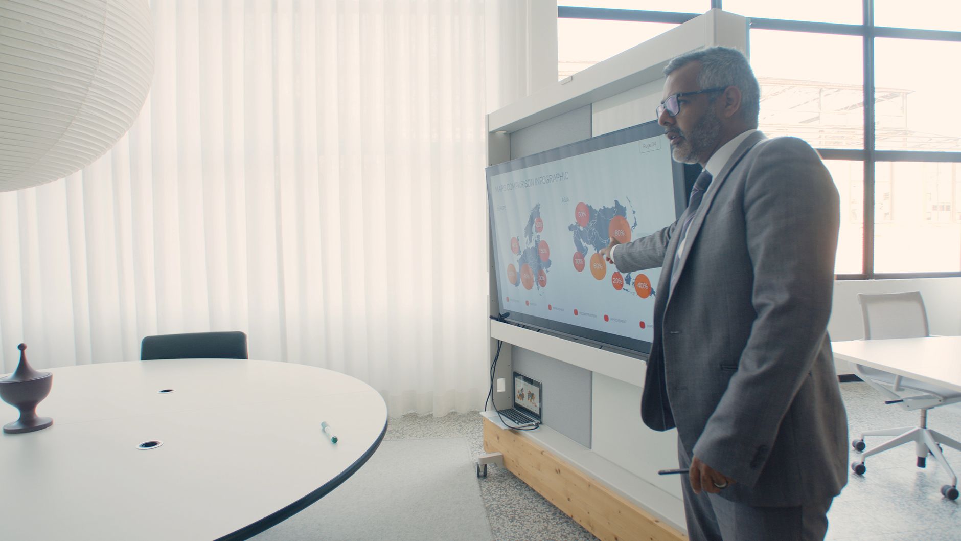 Professional in suit presenting data on screen in a modern office environment.