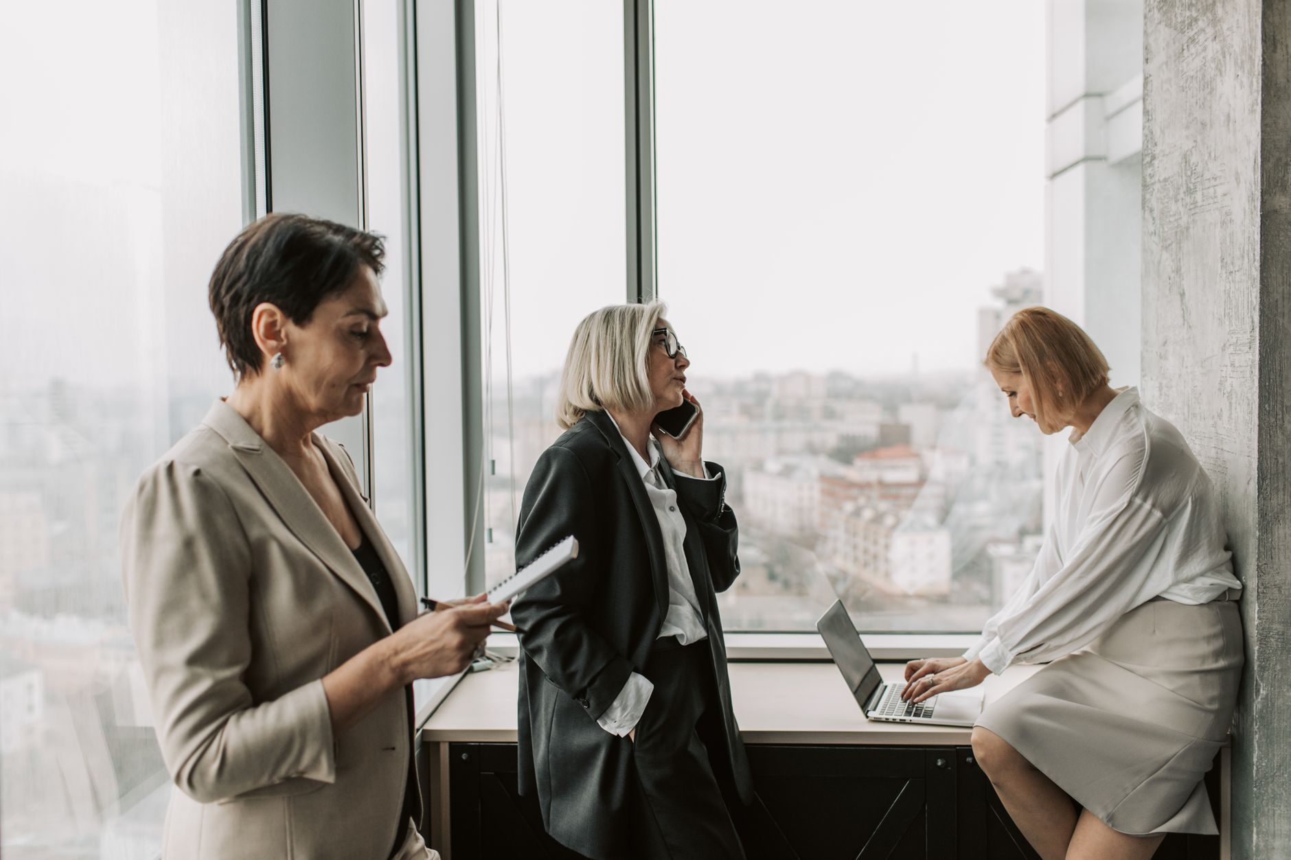 Three mature businesswomen engaged in work at a modern office, promoting teamwork and productivity.