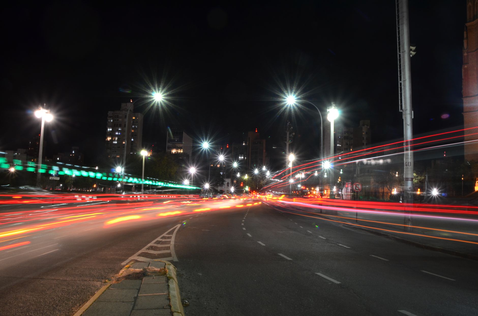 Vibrant night cityscape with moving vehicle light trails on an urban street.