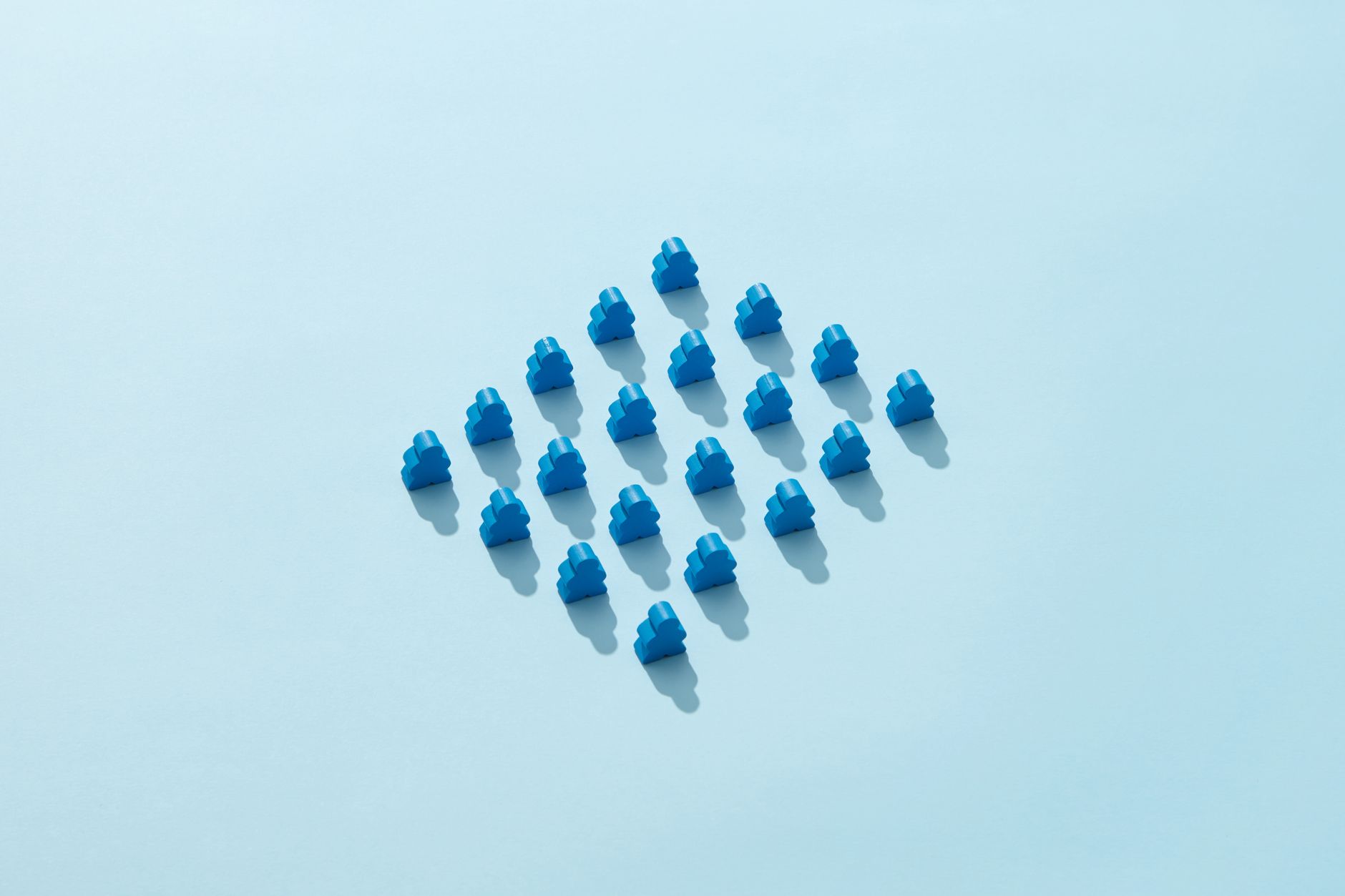 Artistic arrangement of blue meeples on a pastel blue background, highlighting patterns and symmetry.