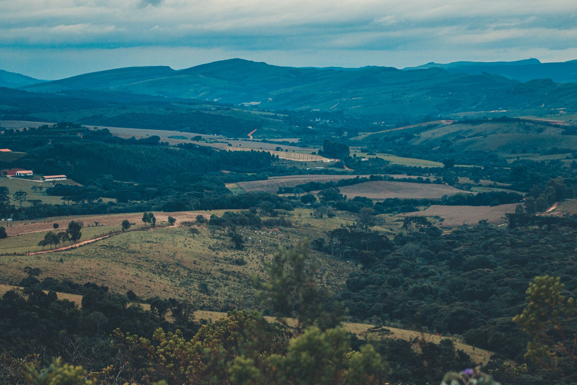A stunning view of rolling hills and lush green valleys under a cloudy sky, offering a tranquil scenic landscape.
