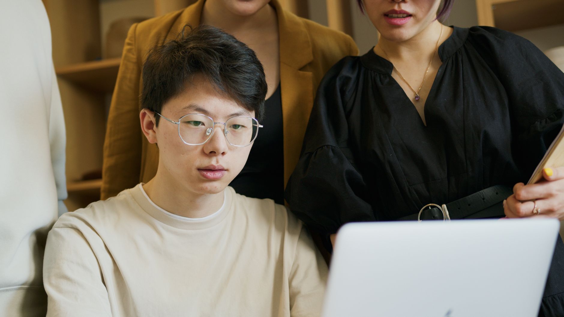 A multicultural team having a collaborative meeting using a laptop in an office setting.