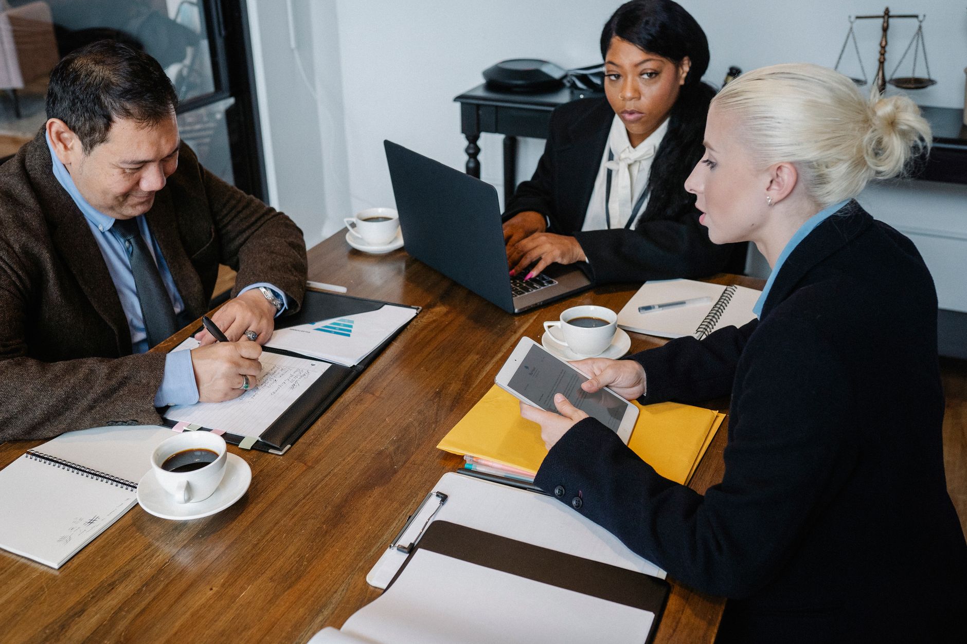 From above of multiracial colleagues in formal outfit working with papers laptop and tablet at table