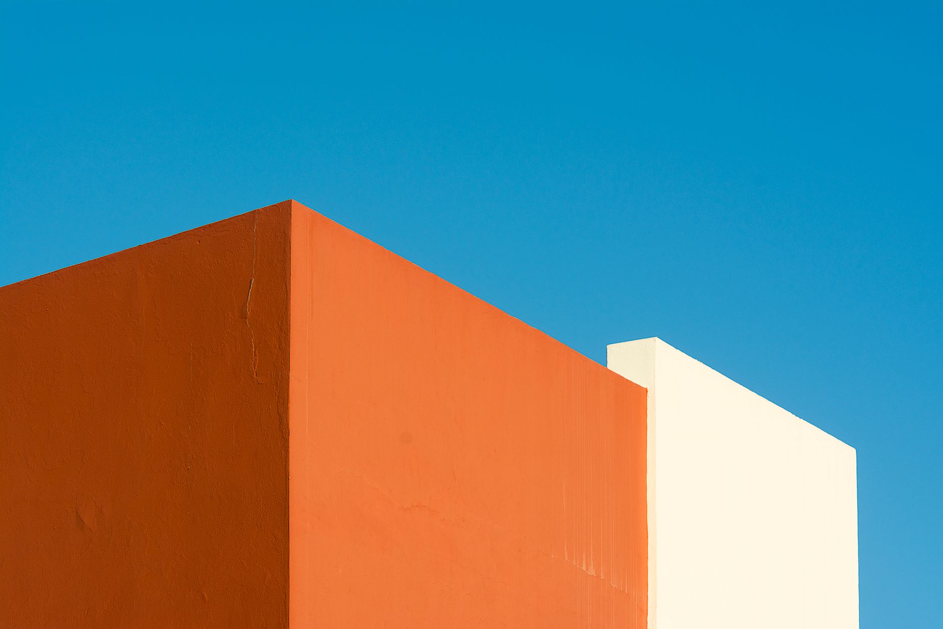 Abstract view of colorful building walls against a clear blue sky, showcasing minimalist architecture.