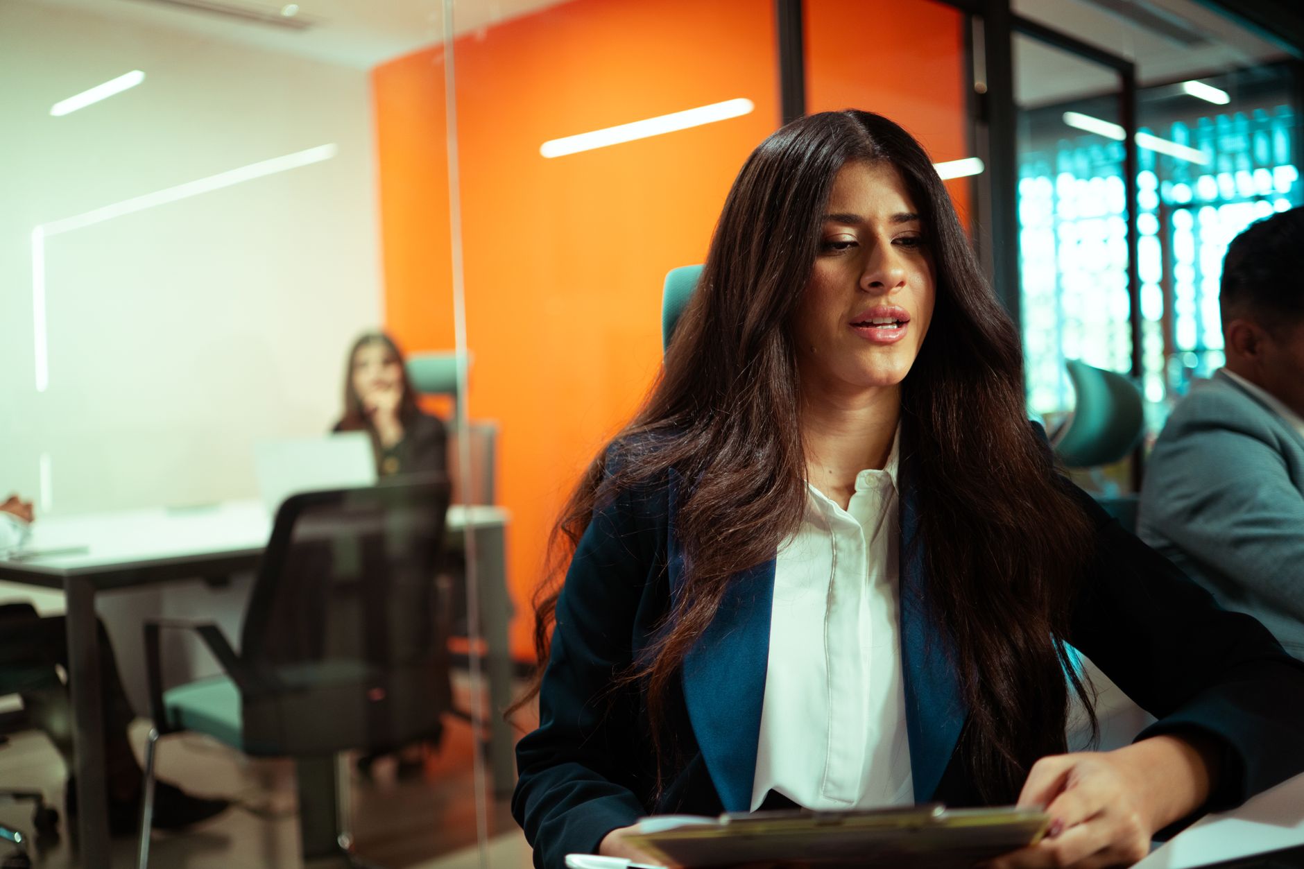 Two business professionals in a modern office setting during a team meeting.
