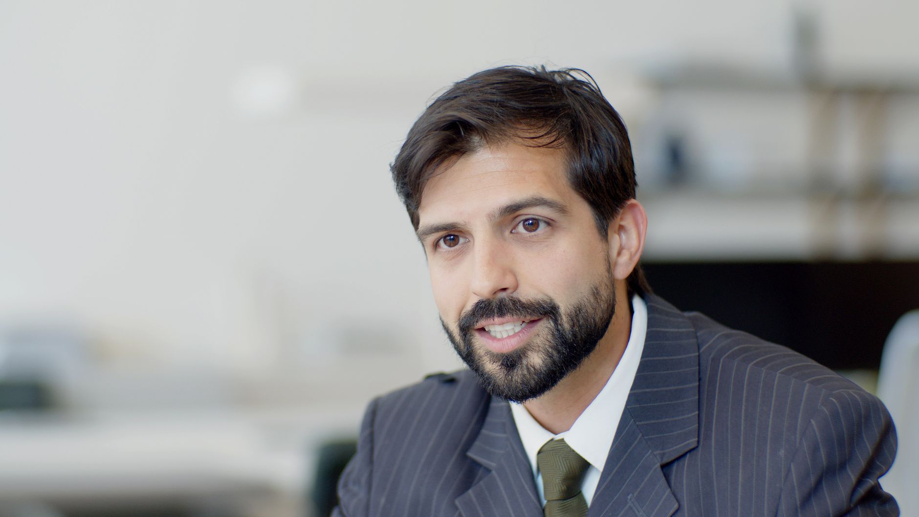 Businessman in suit and tie with a blurred office background.
