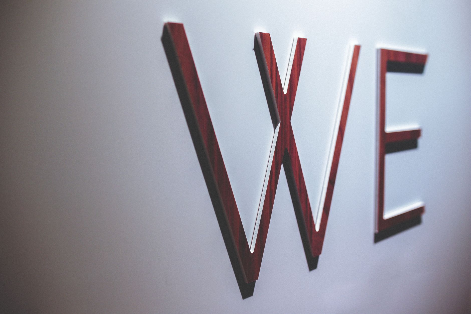Abstract image depicting wooden letters spelling 'WE' on a white wall.