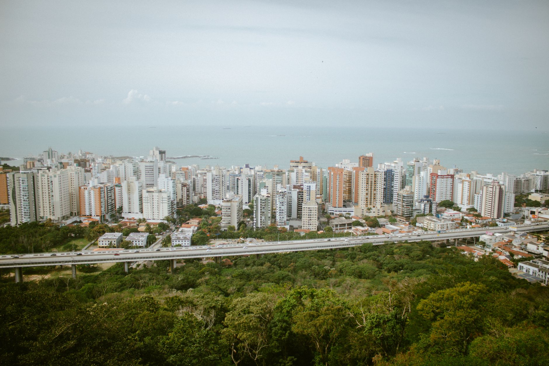 A panoramic aerial view of Vitória's coastal cityscape in Brazil, showcasing skyscrapers and lush greenery.