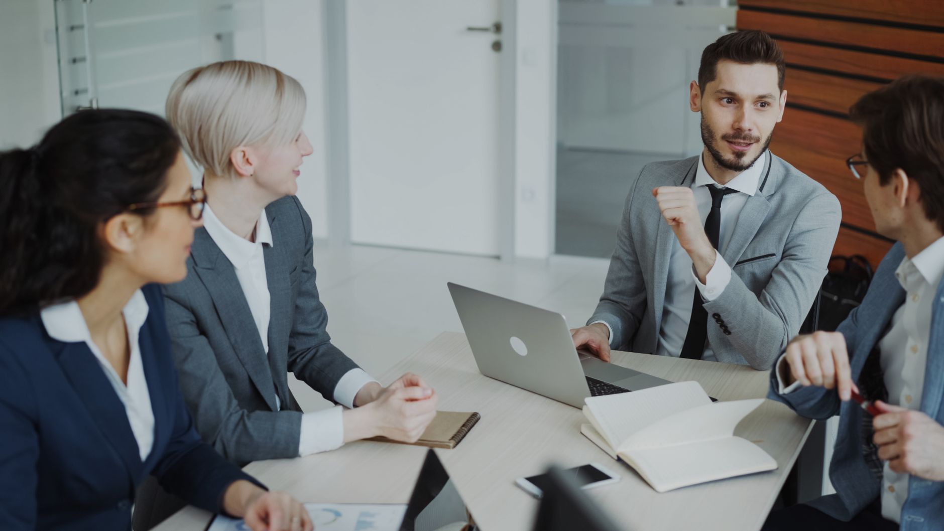 Business professionals engaged in a meeting around a conference table in a modern office space.