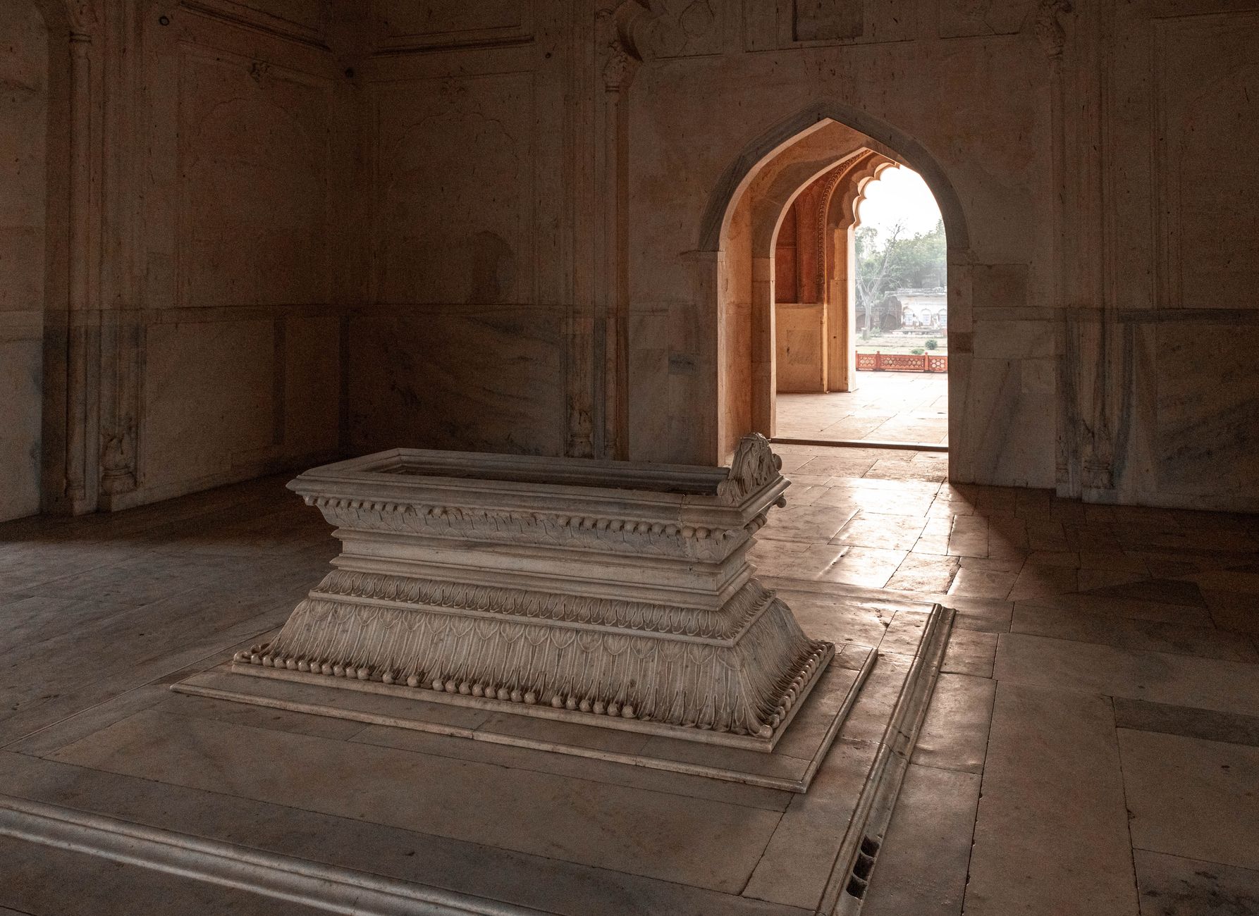 Intricate stone tomb inside historic Mughal architecture in Delhi, India.