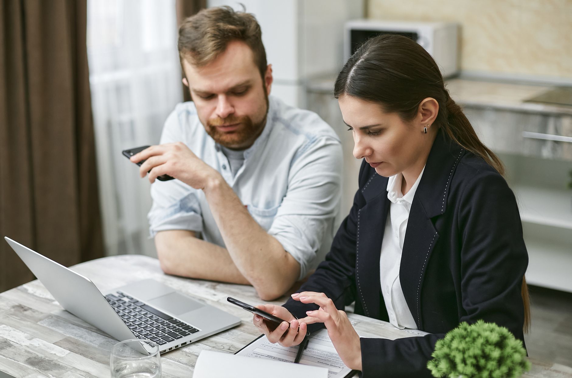 Business professionals working together on mobile devices and laptop in an office setting.