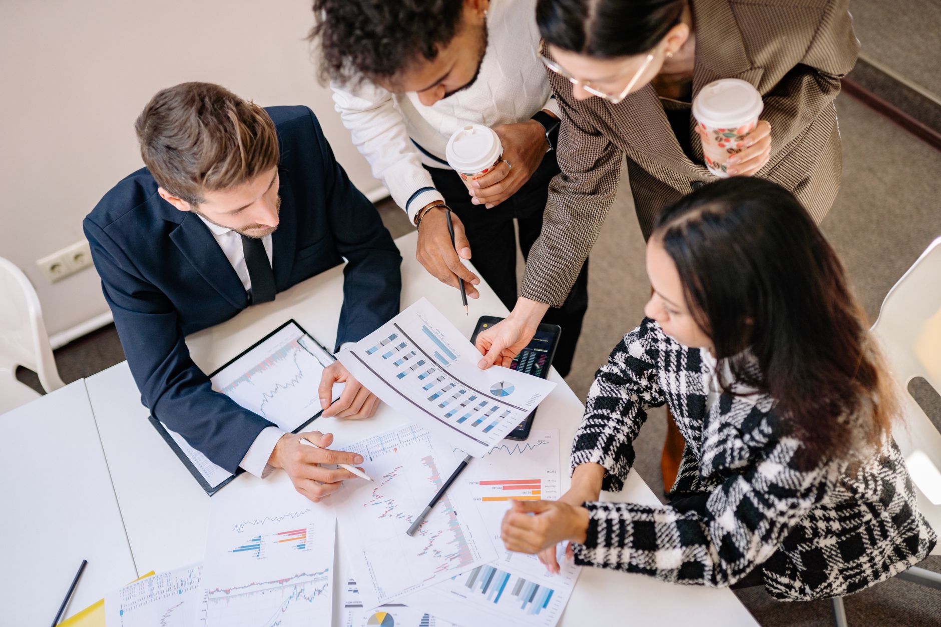 A diverse team in business attire collaborates over graphs and charts for a successful project.