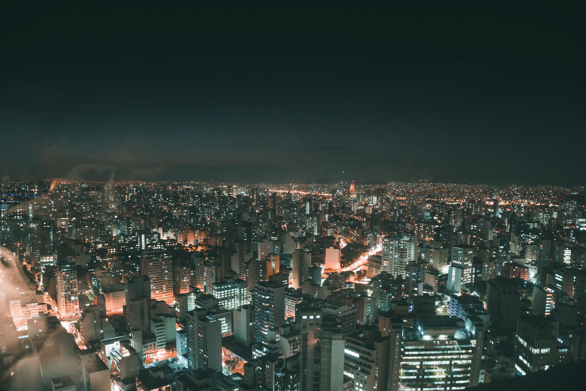 A breathtaking aerial view of city skyscrapers illuminated at night, showcasing urban life and glowing city lights.