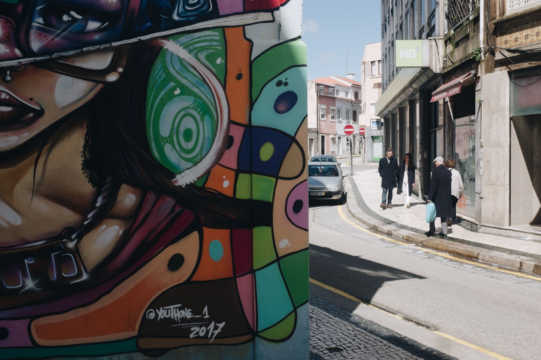 Colorful street art mural with pedestrians and cars in a city setting.