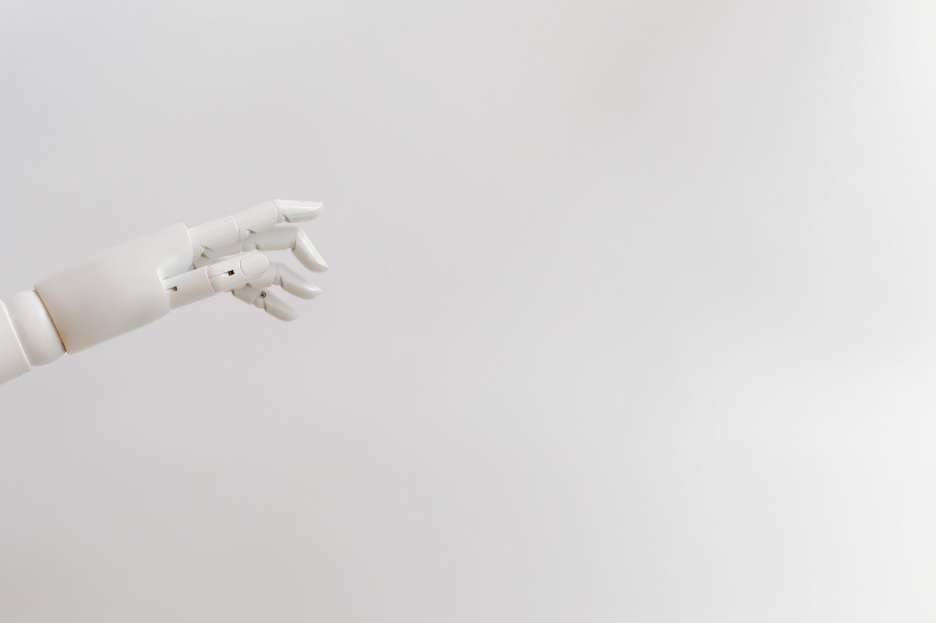 Minimalist image of a robotic hand reaching out on a white background.
