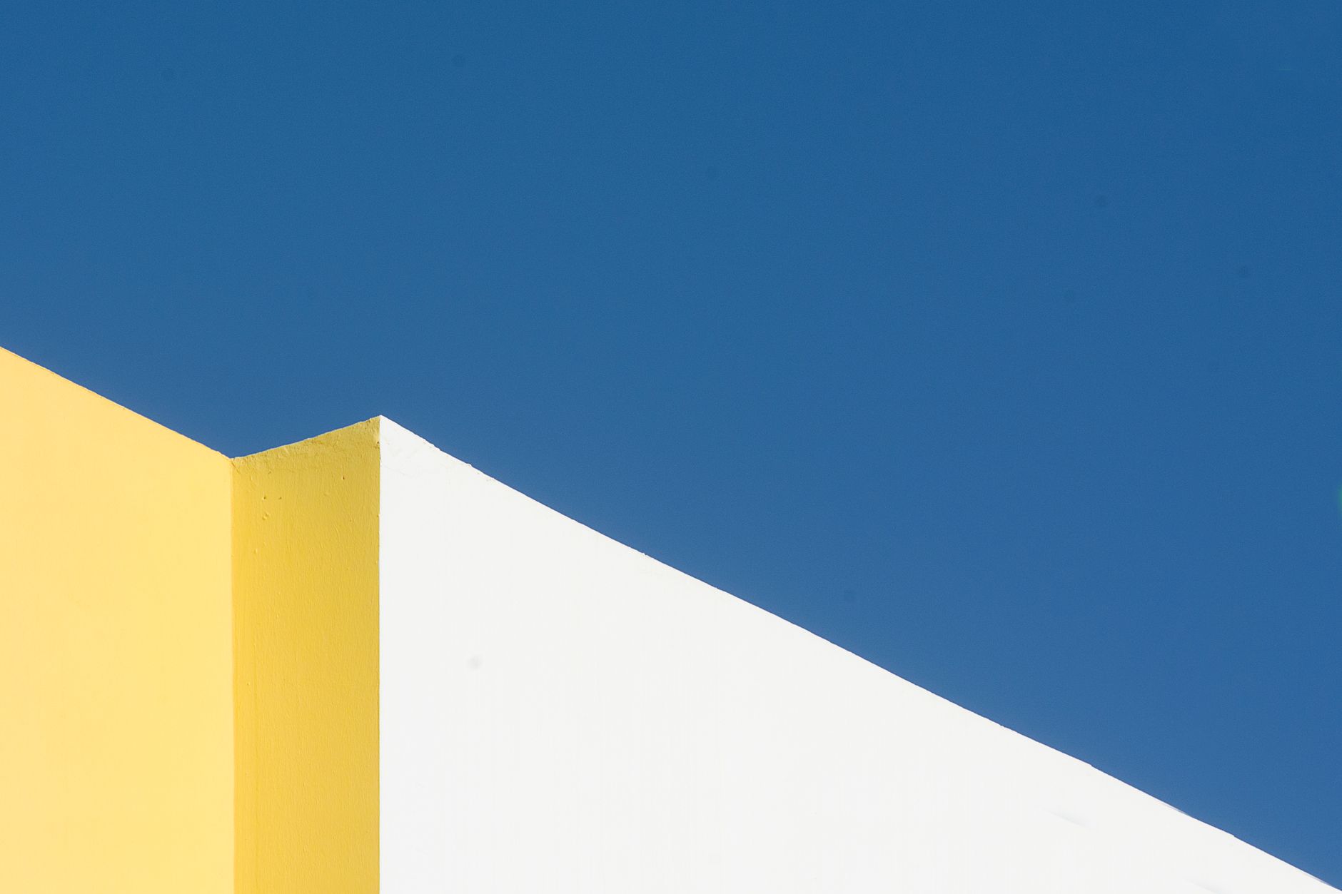 Minimalist architecture featuring bold yellow and white against a vivid blue sky.