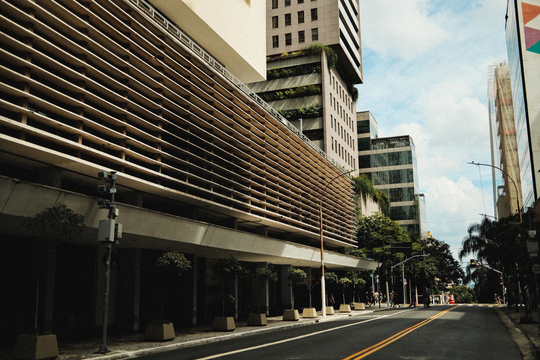 A bustling urban street featuring modern architecture and vertical gardens under a bright sky.