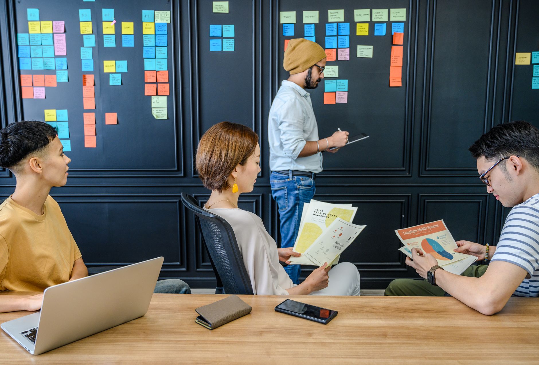 Group of colleagues engaged in a brainstorming session with sticky notes and documents in a modern office setting.