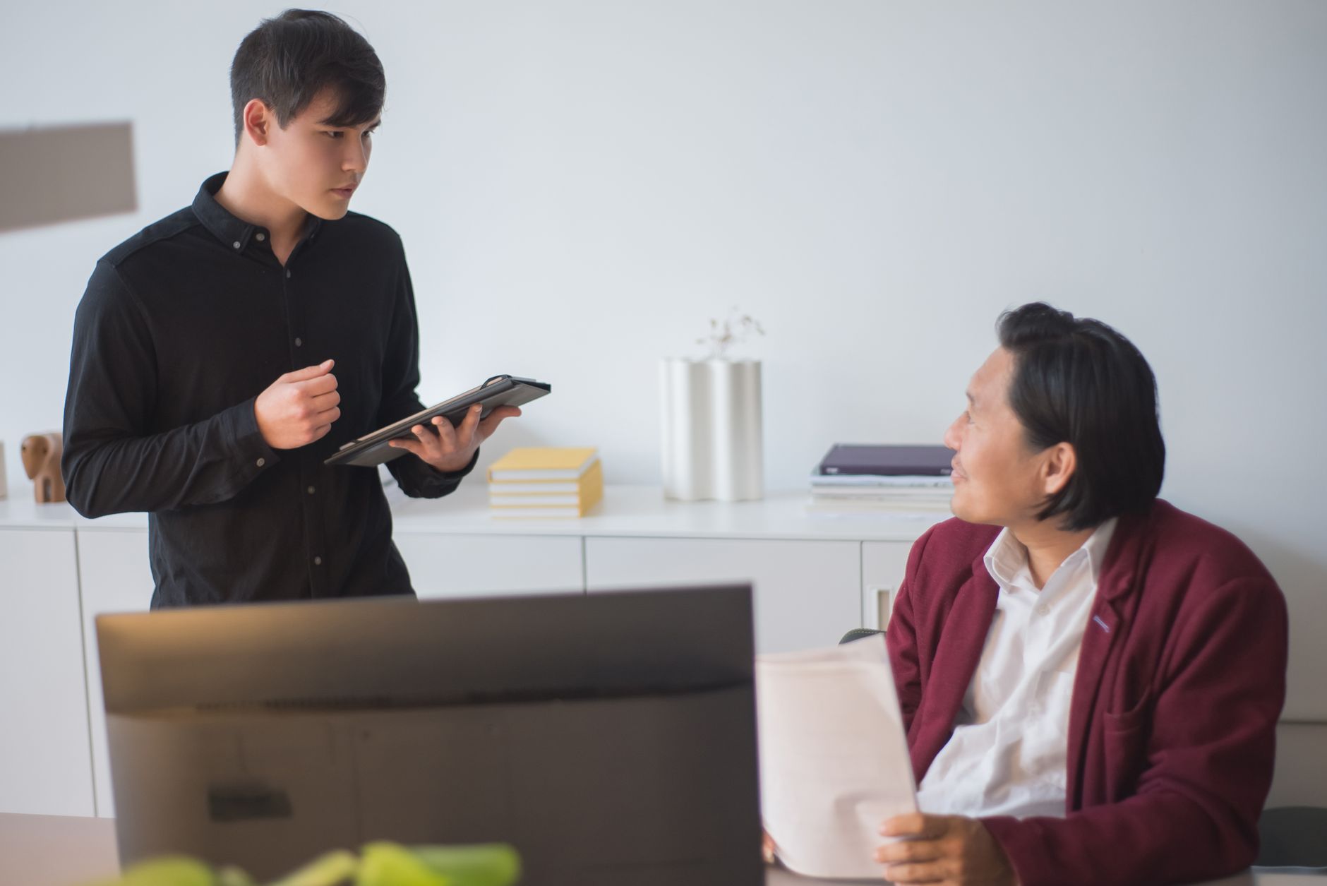 Two businessmen discussing a project in a modern office setting.