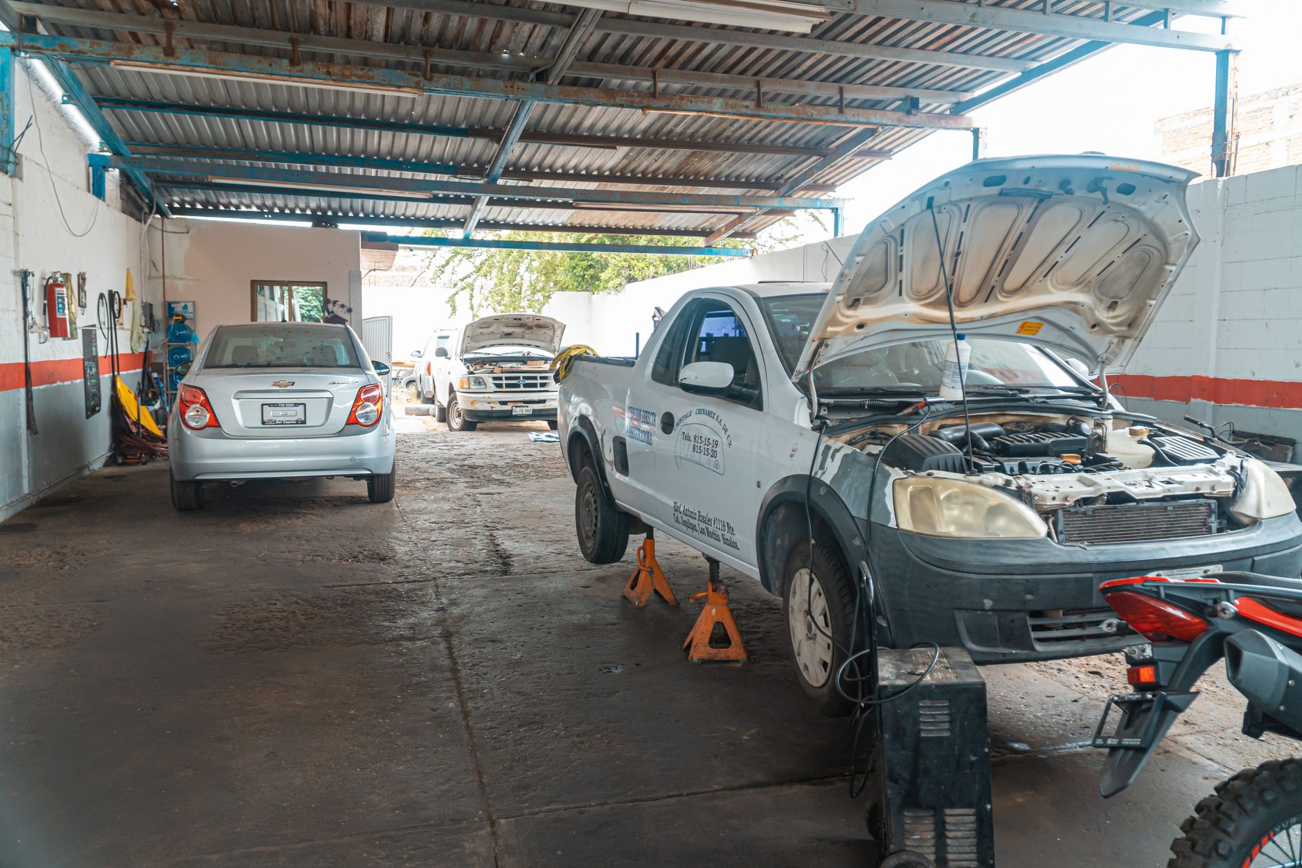 Indoor car repair garage with multiple vehicles under maintenance, showcasing a bustling automotive environment.