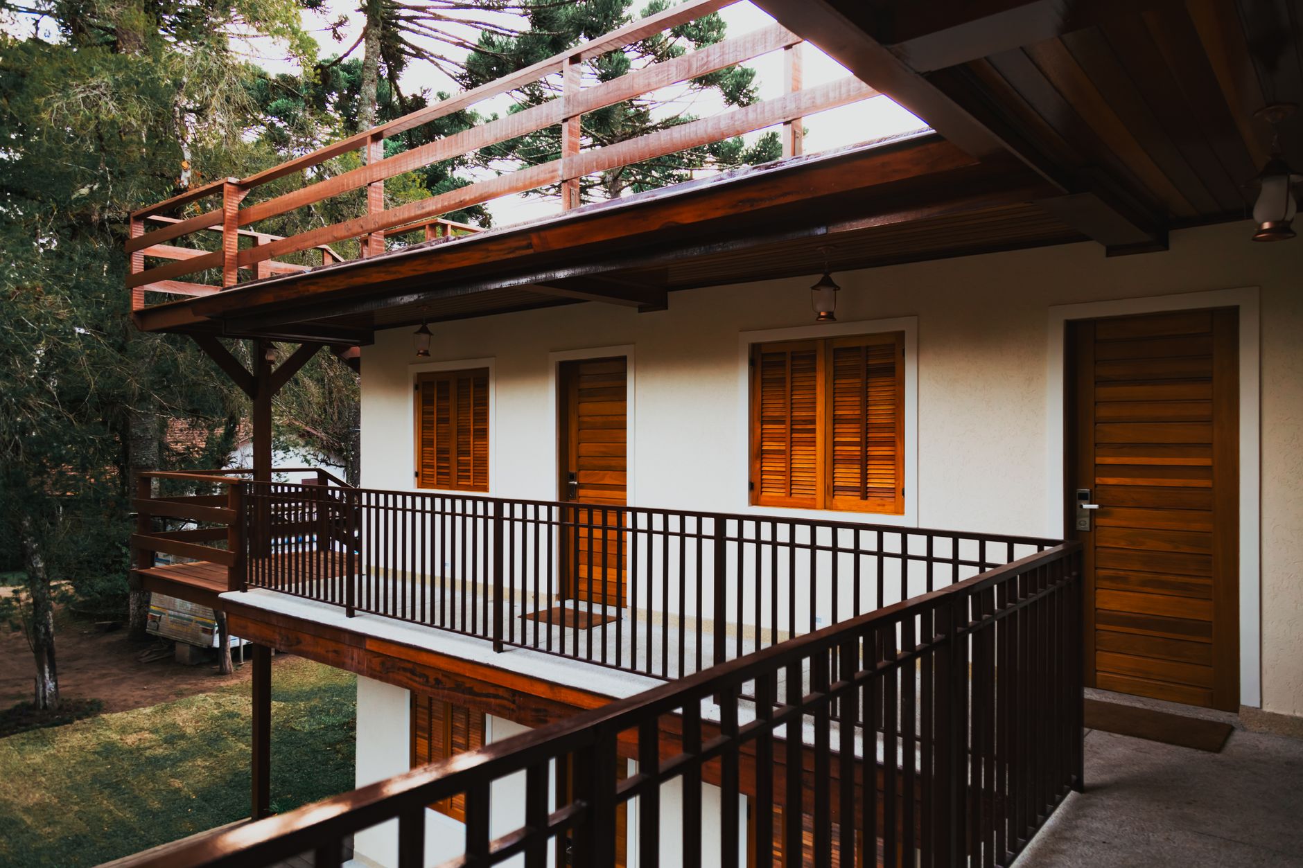 Serene wooden lodge featuring balconies, doors, and windows surrounded by lush greenery.