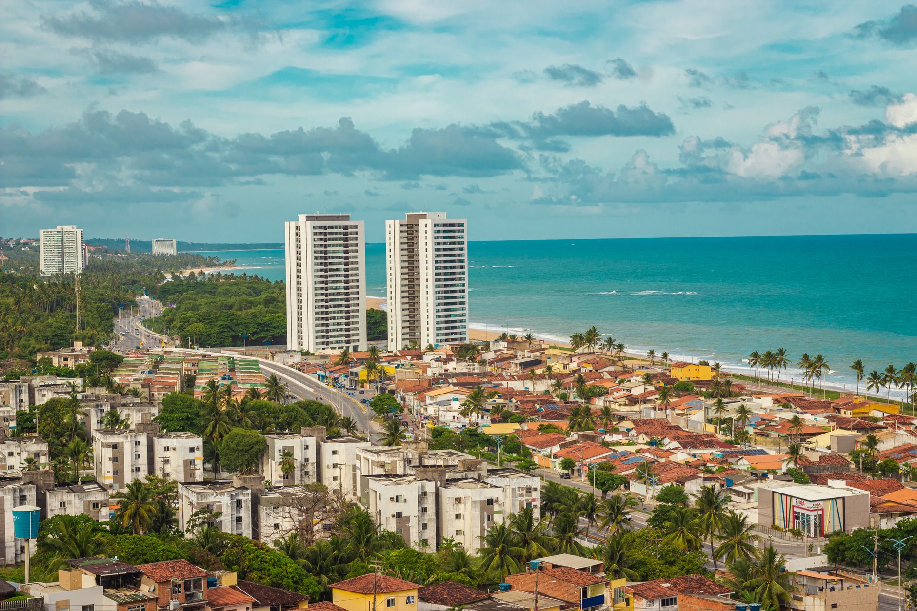A vibrant cityscape view of Maceió, Brazil with beachside buildings and lush greenery.