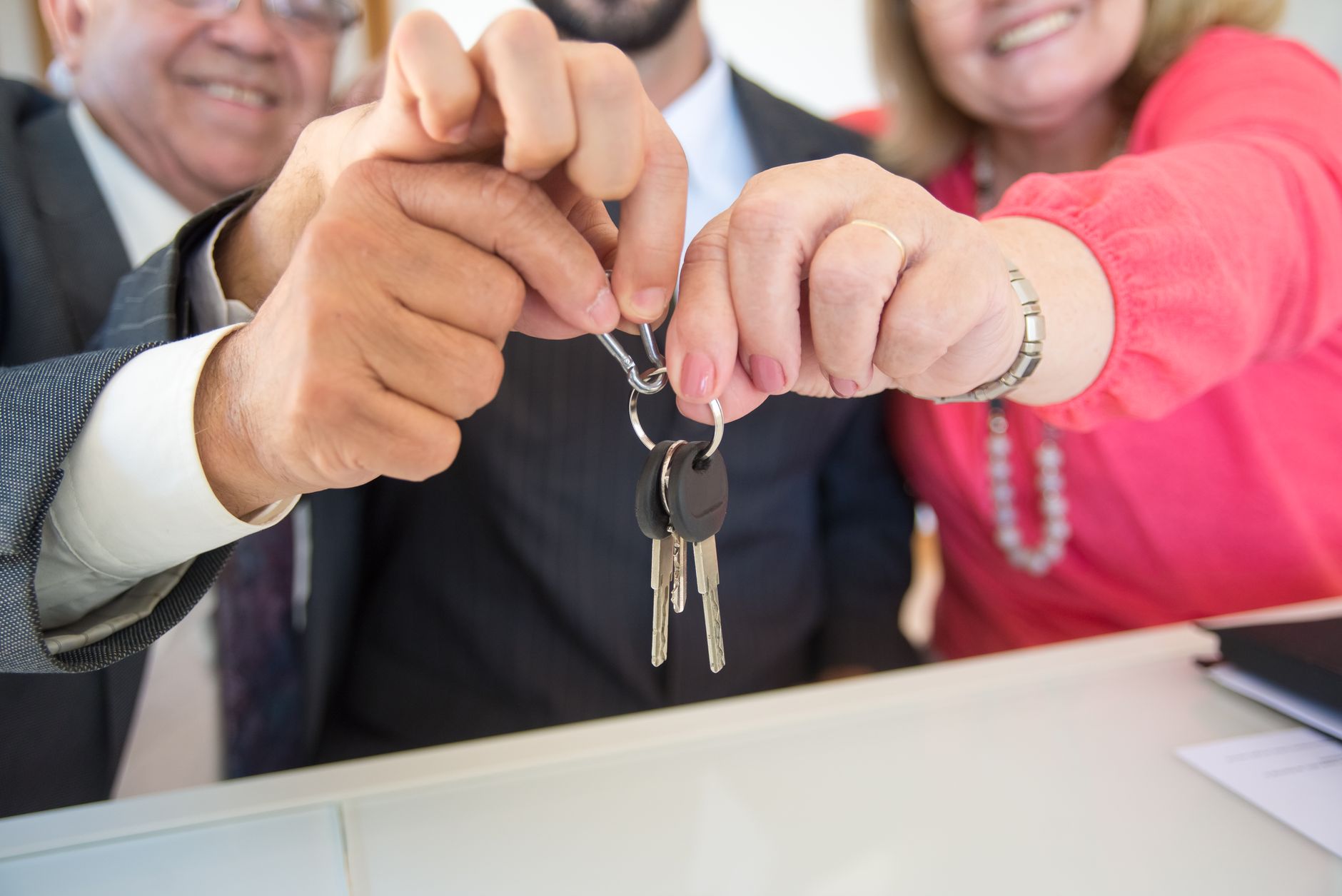 Business colleagues celebrating a successful deal with a handshake and keys exchange.