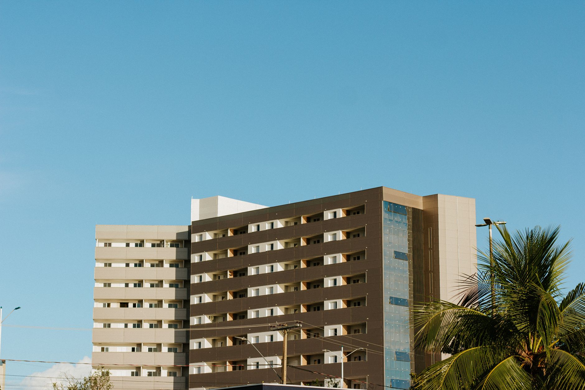 Contemporary apartment building in Palmas, Brazil with clear blue skies and palm trees.