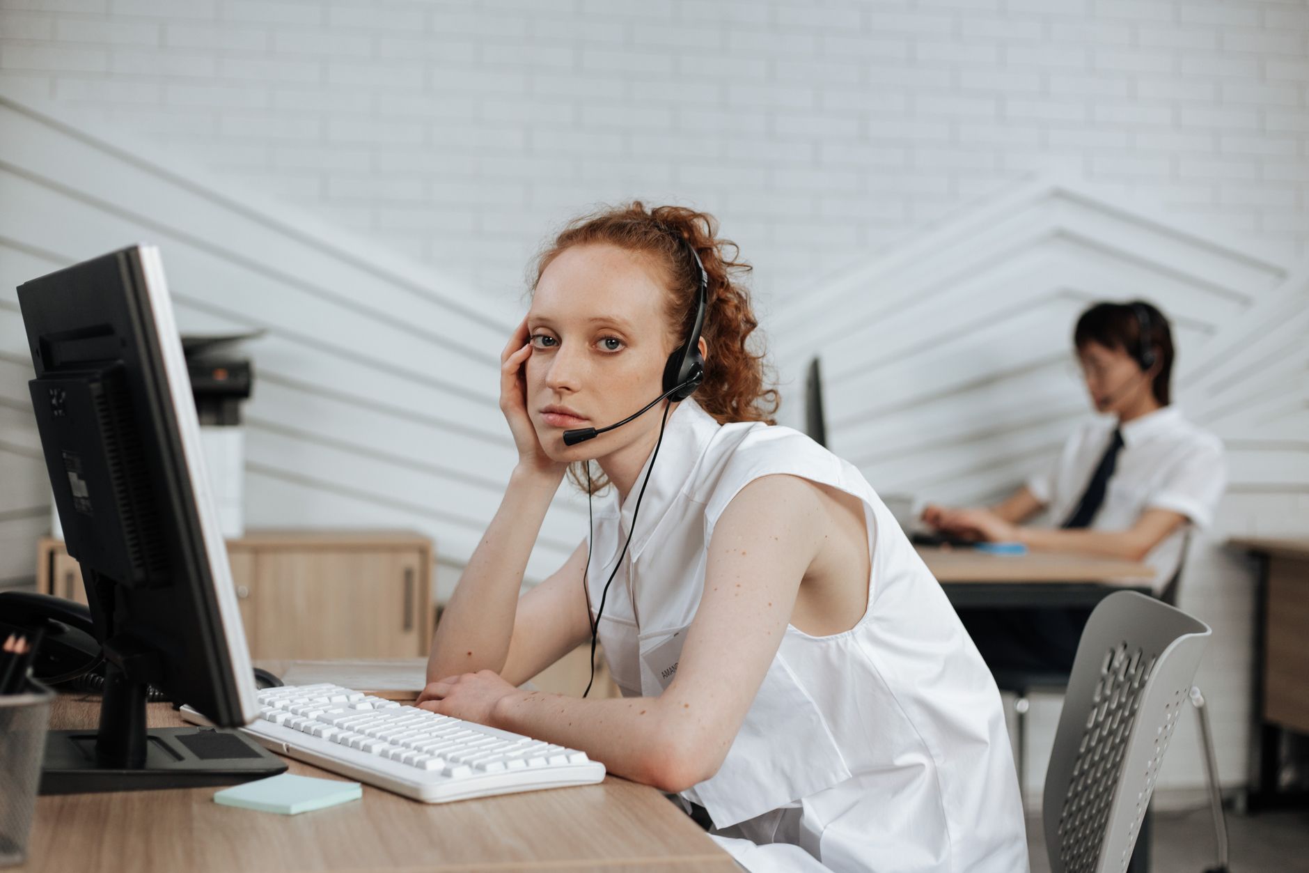Focused call center agent with headset working at a modern office desk.