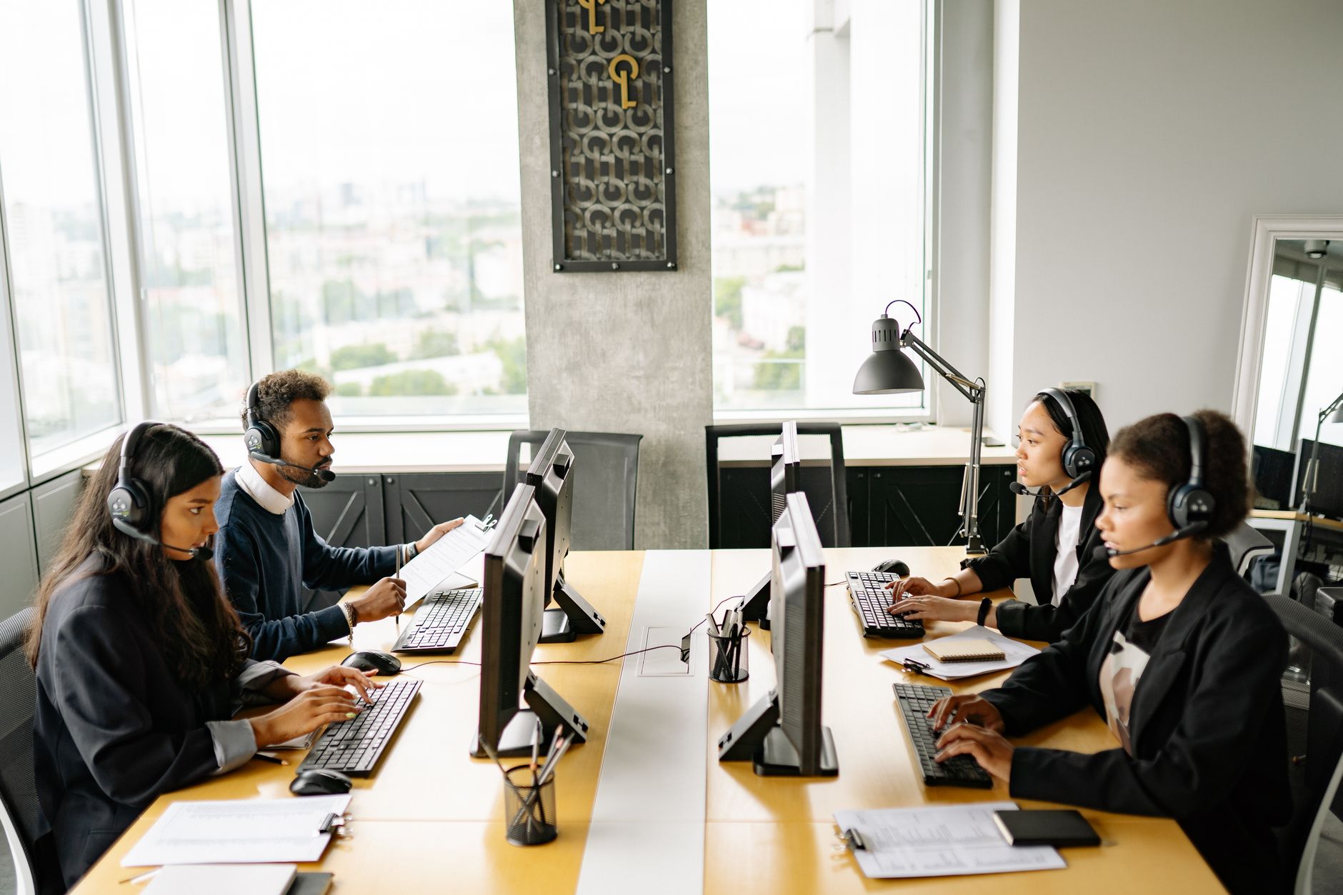Group of diverse employees working together in a modern office setting, focusing on customer service.