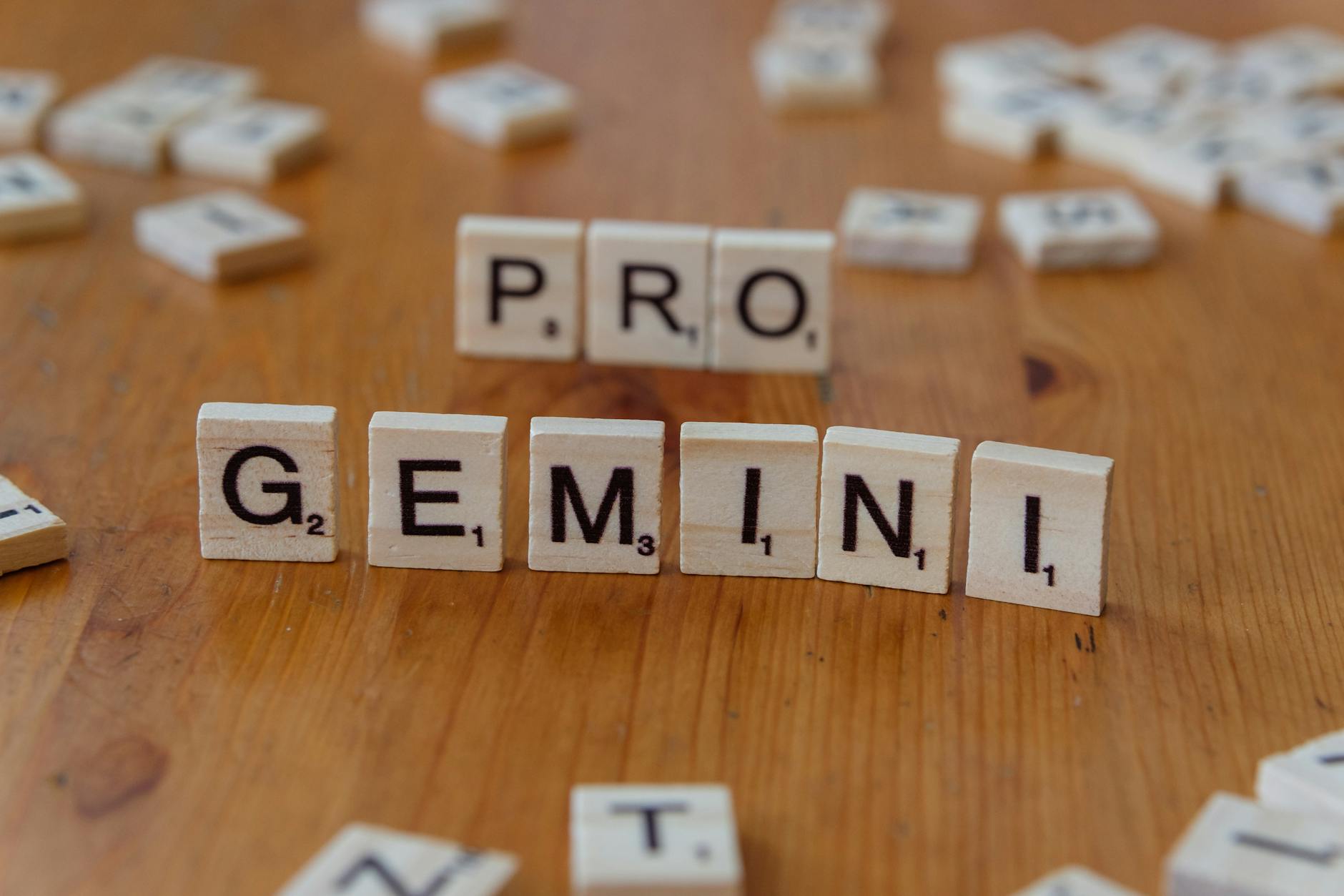 Scrabble tiles spelling out Google and Gemini on a wooden table, focusing on AI concepts.