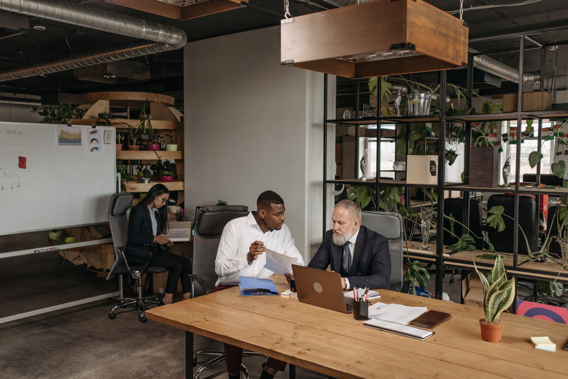 A diverse group of professionals discussing work documents in a contemporary office setting.