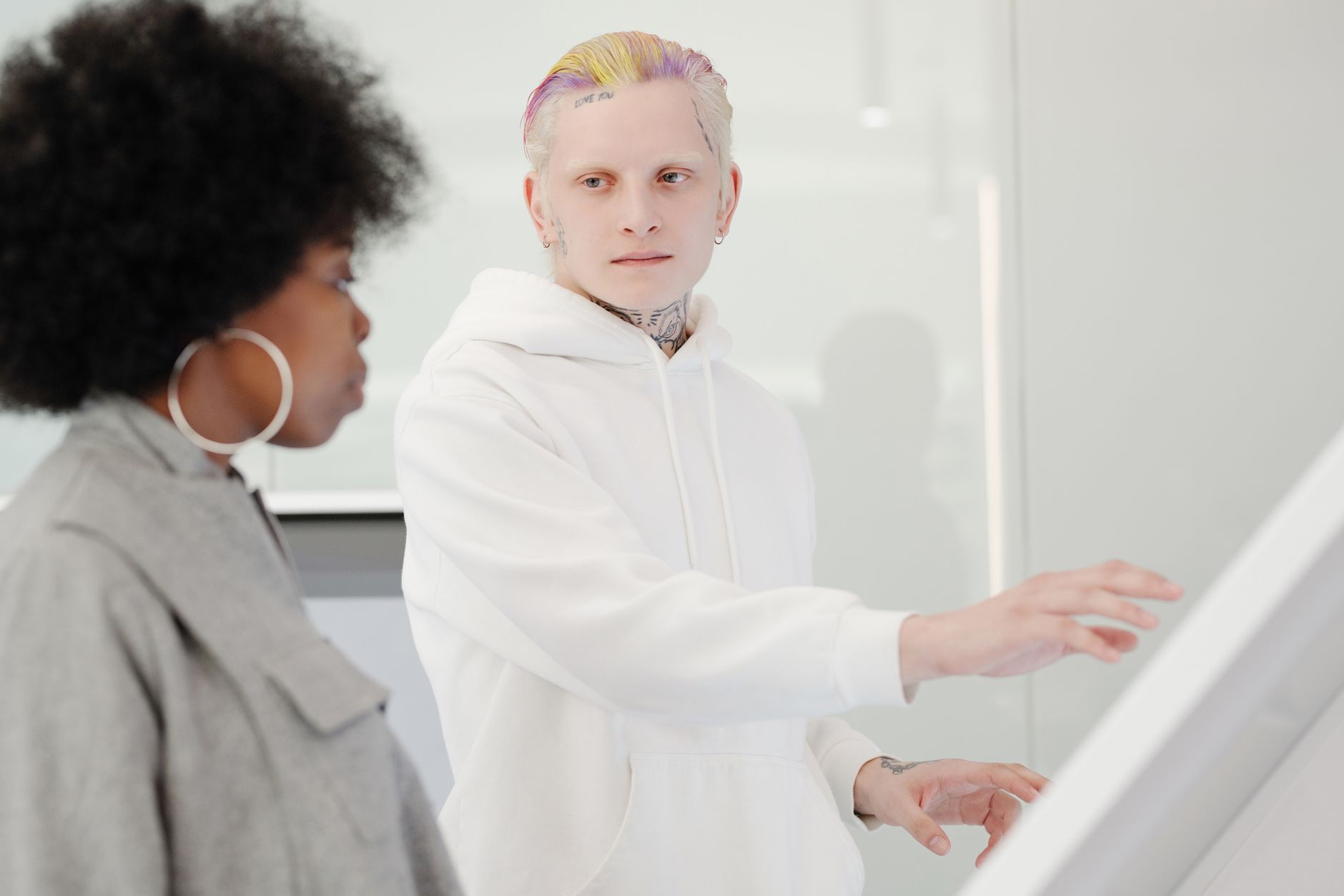 Two colleagues interacting in a modern workspace, wearing stylish attire.