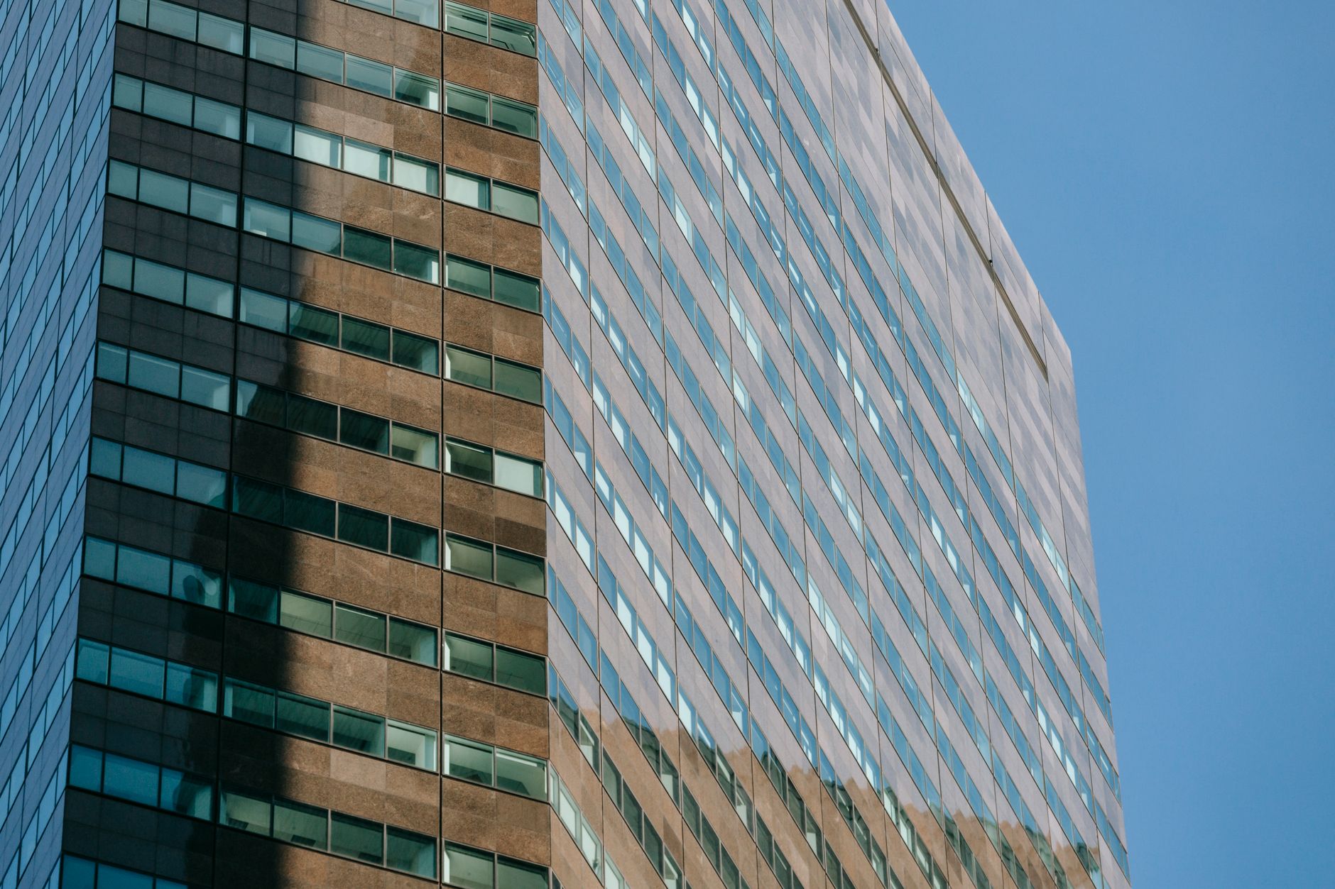 Low angle of tall contemporary multistory office building with reflecting walls located in central district