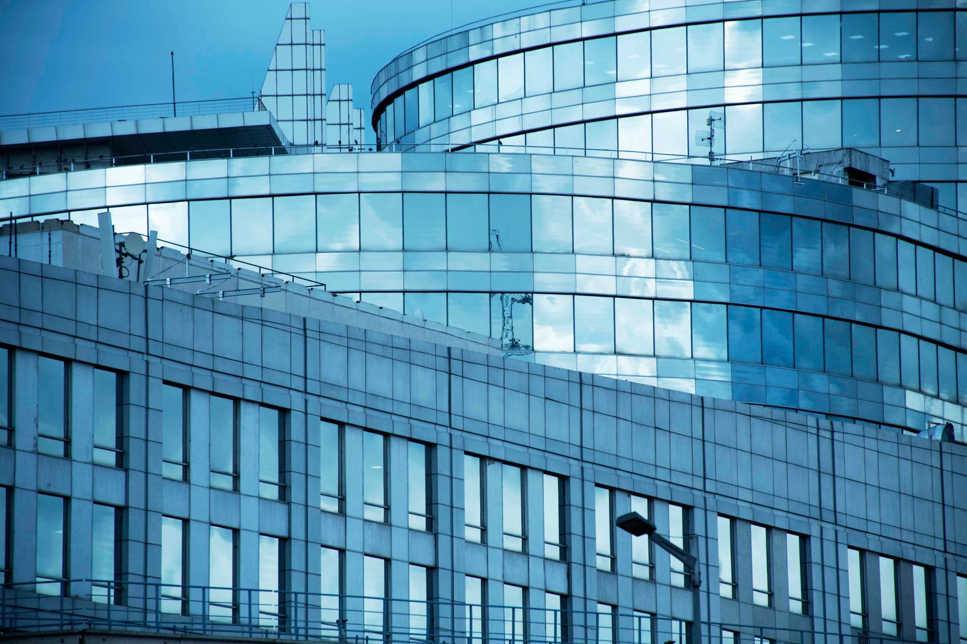 Detail of a modern city's sleek glass and steel architecture under a blue sky.