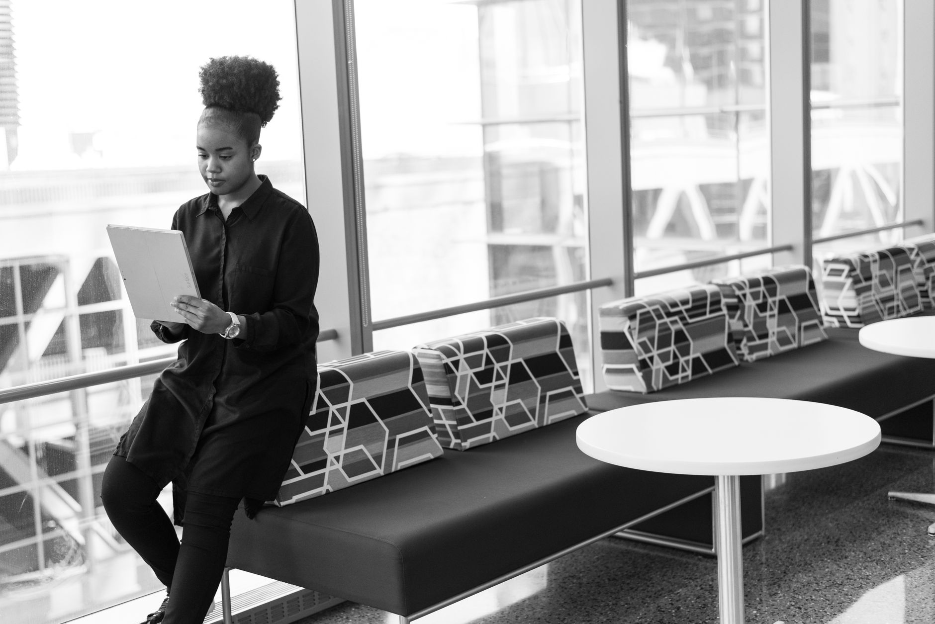 Black and white portrait of woman using tablet in modern office space.