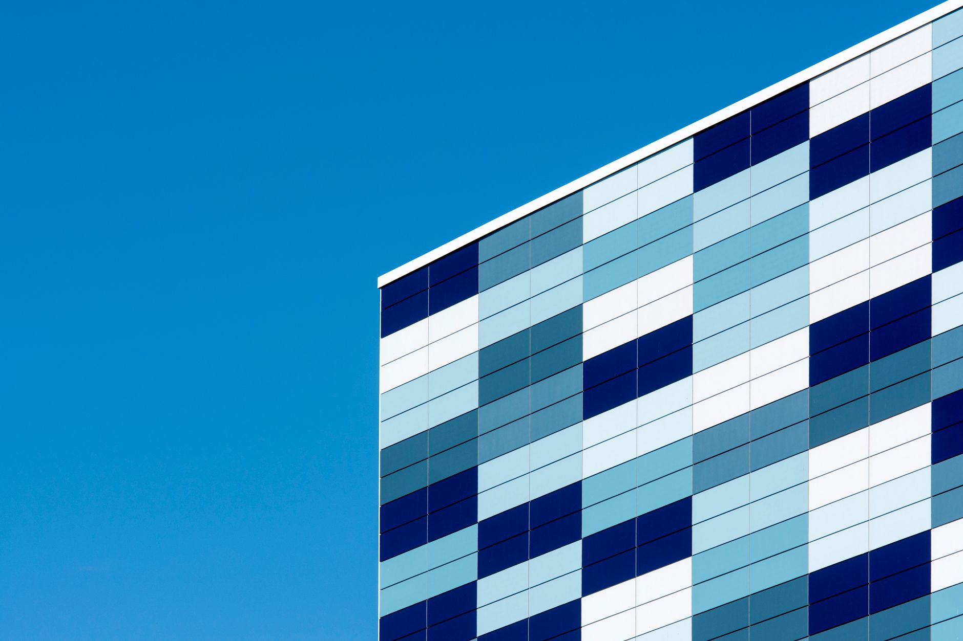 A modern building facade with geometric blue patterns against a clear sky, showcasing contemporary architecture.