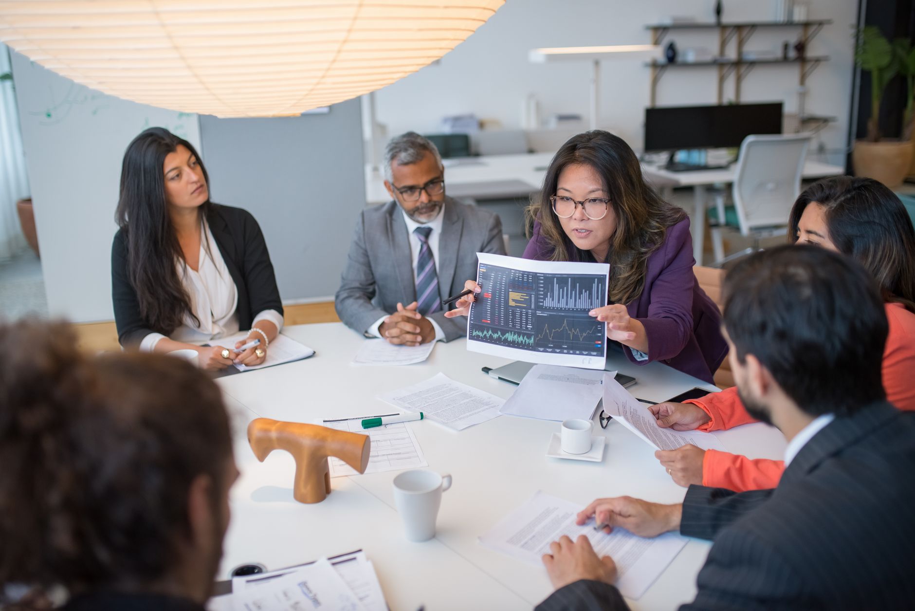 Multicultural team discussing analytics in a professional business meeting setting with data charts.