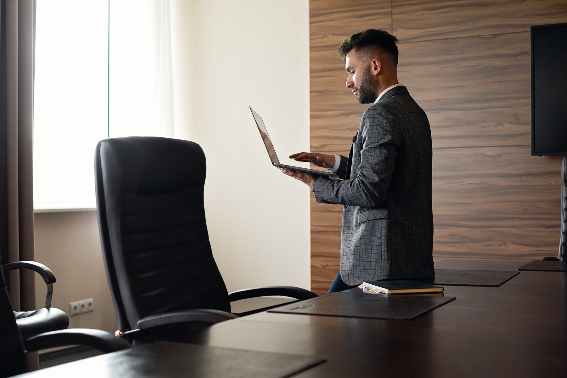Professional man working on a laptop in a stylish office environment, showcasing modern workplace dynamics.