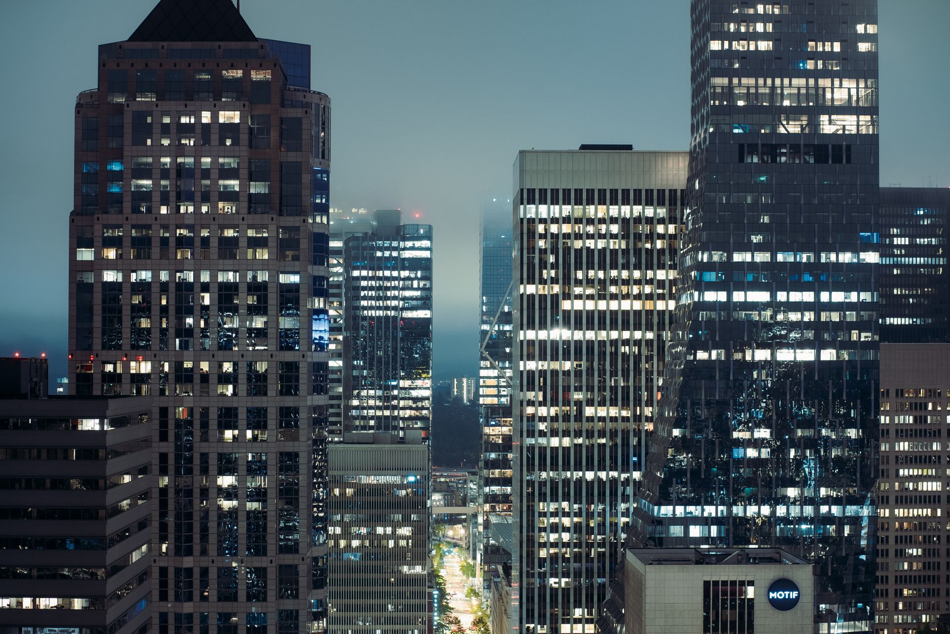 Seattle's modern skyscrapers lit up at night in fog, showcasing urban architecture.