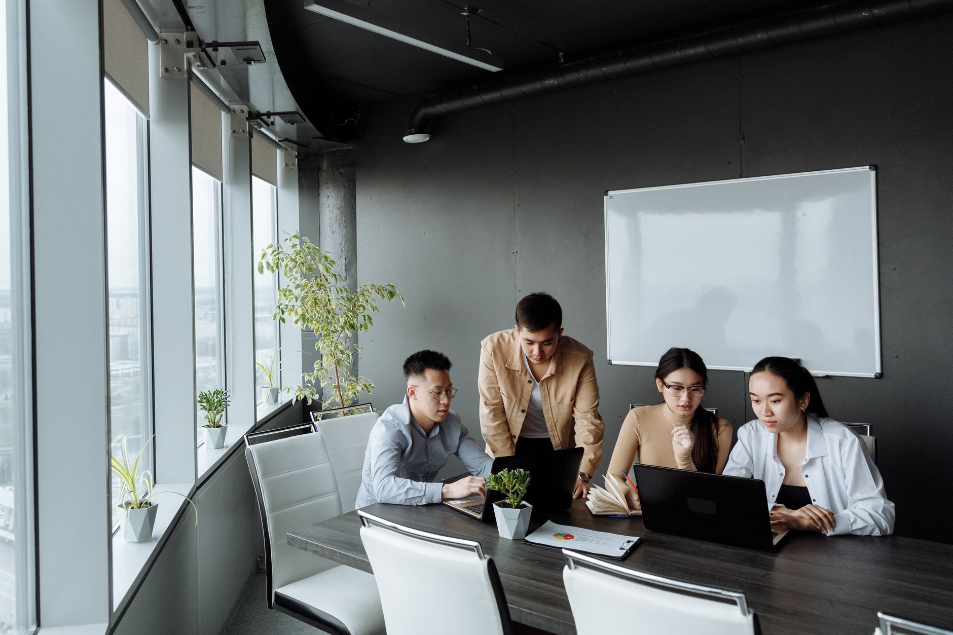 Diverse group of professionals collaborating around laptops in a modern office setting.