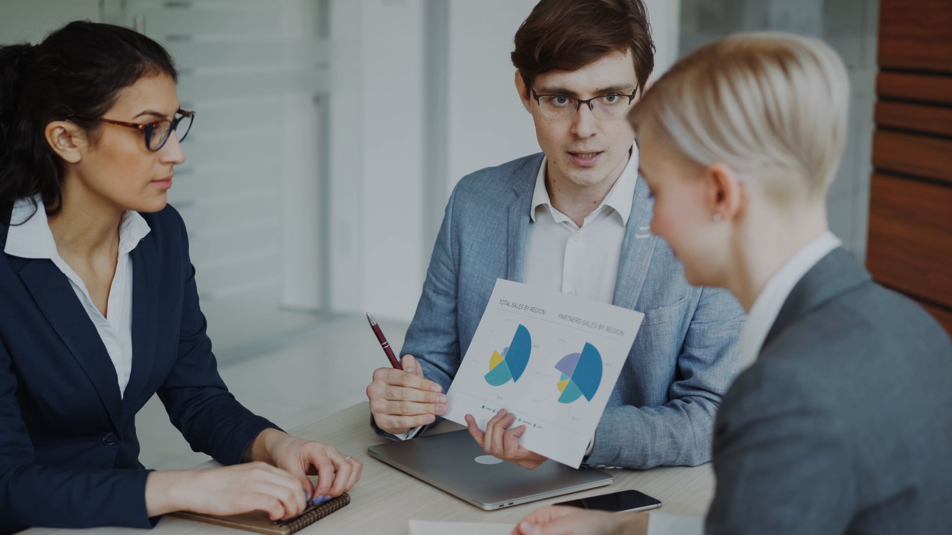 Team of professionals discussing sales strategies with charts in a modern office.
