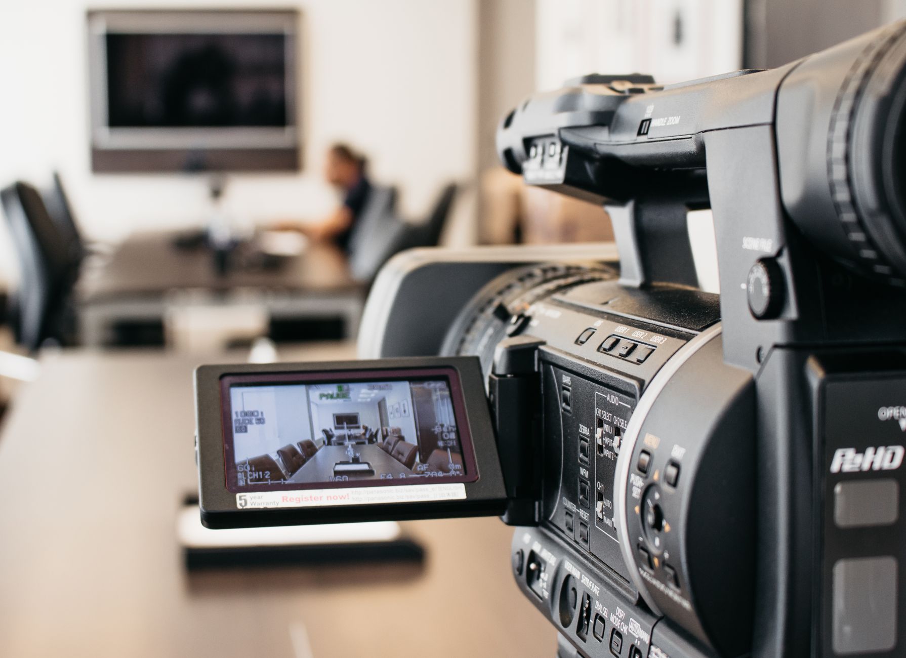 Close-up of professional video camera recording in modern office environment.
