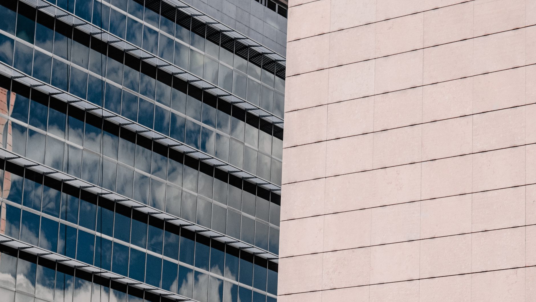 Close-up of a modern glass skyscraper reflecting clouds on its facade in Colombia.