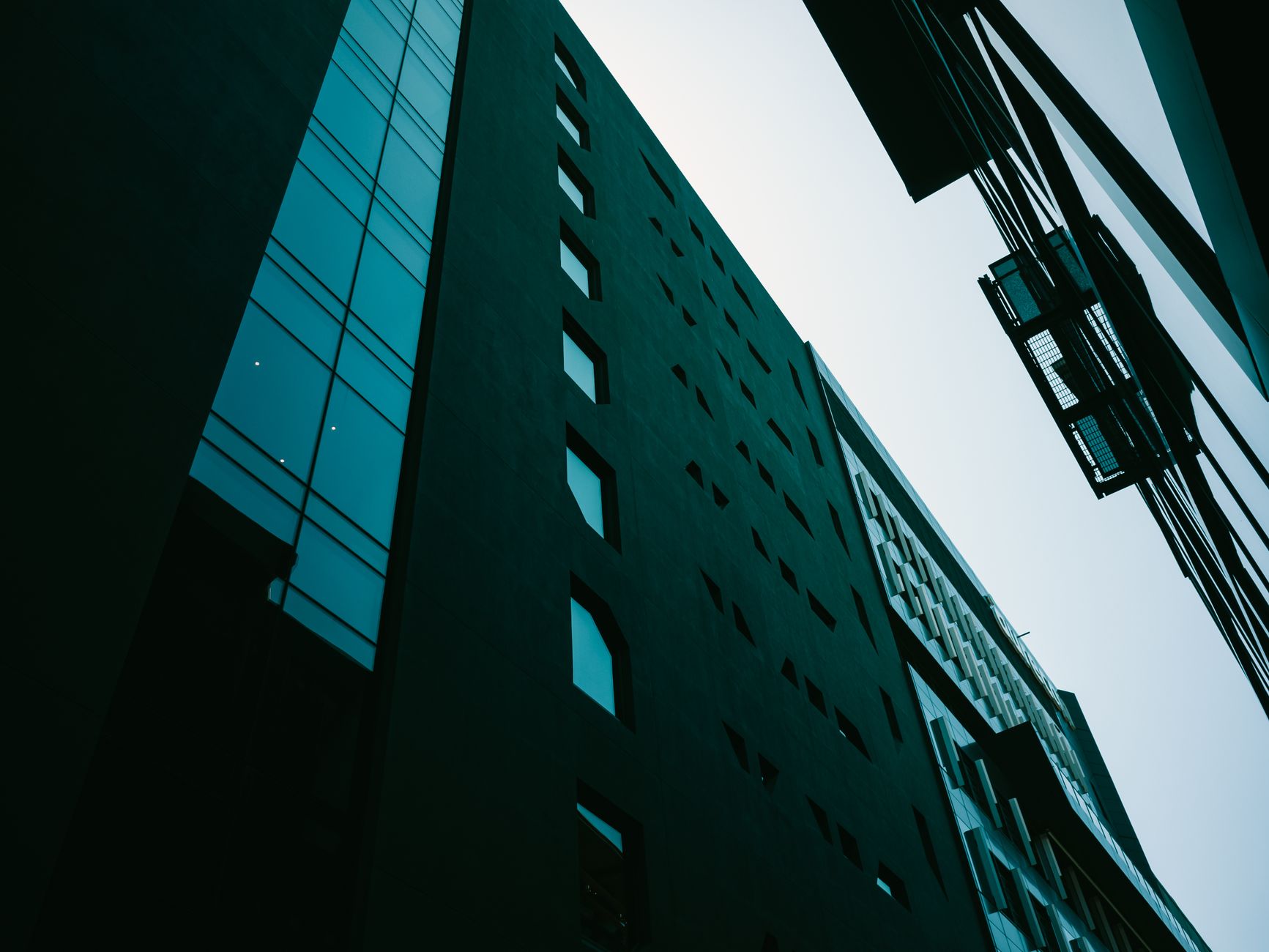 Low angle view of modern buildings with overcast sky and distinctive architecture.
