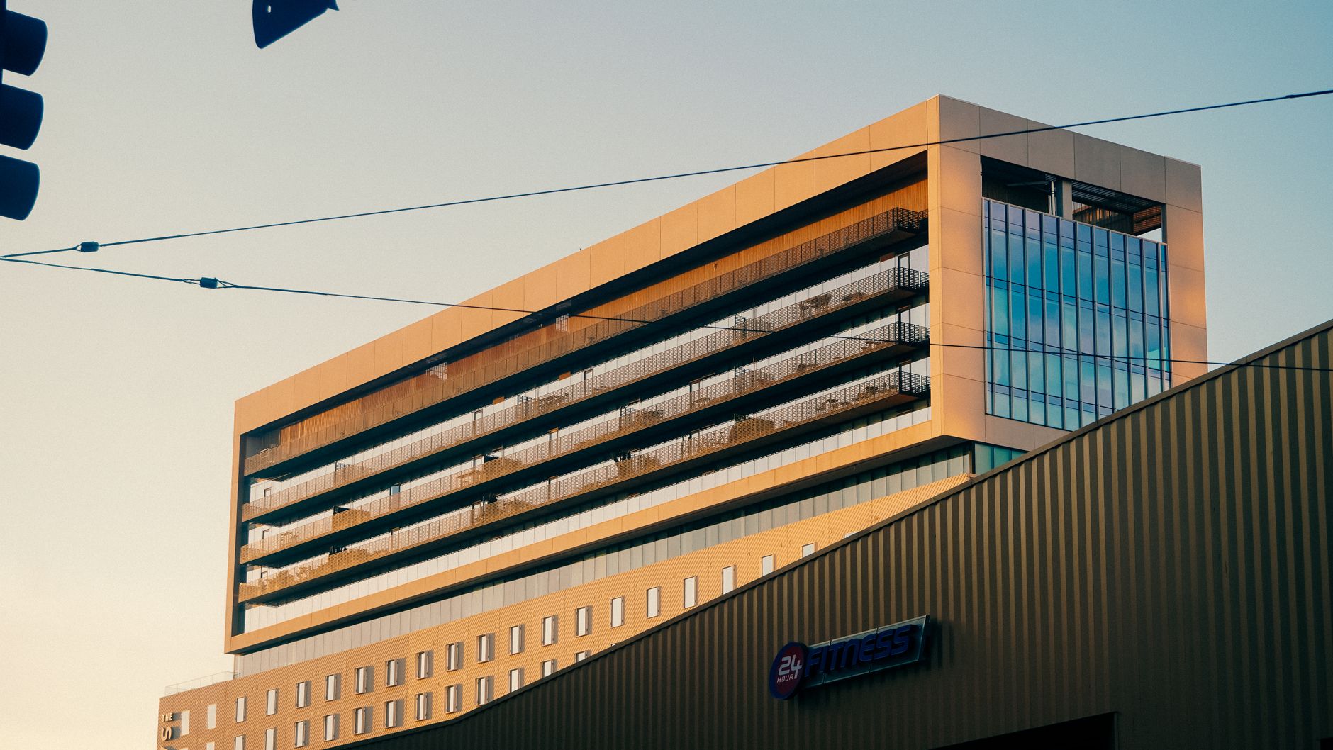 A modern office building exterior photographed at sunset, featuring a gym sign.