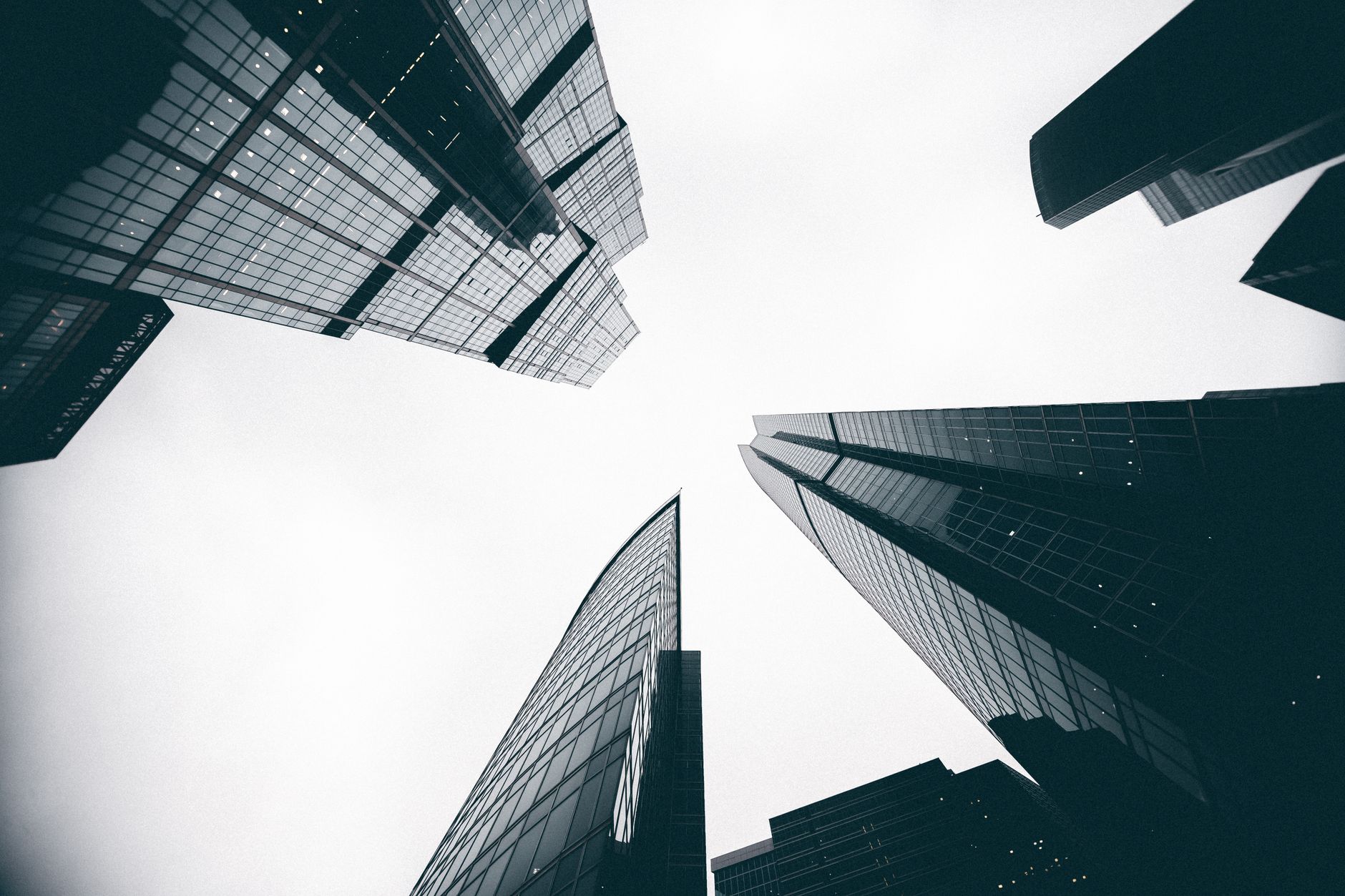 Low angle black and white photo of skyscrapers reaching towards the sky with a dramatic perspective.