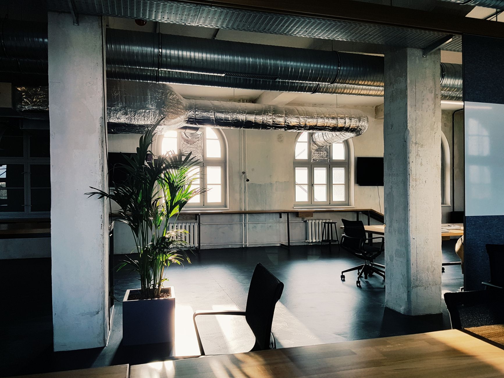 Bright modern office interior with industrial design elements and natural light through large windows.