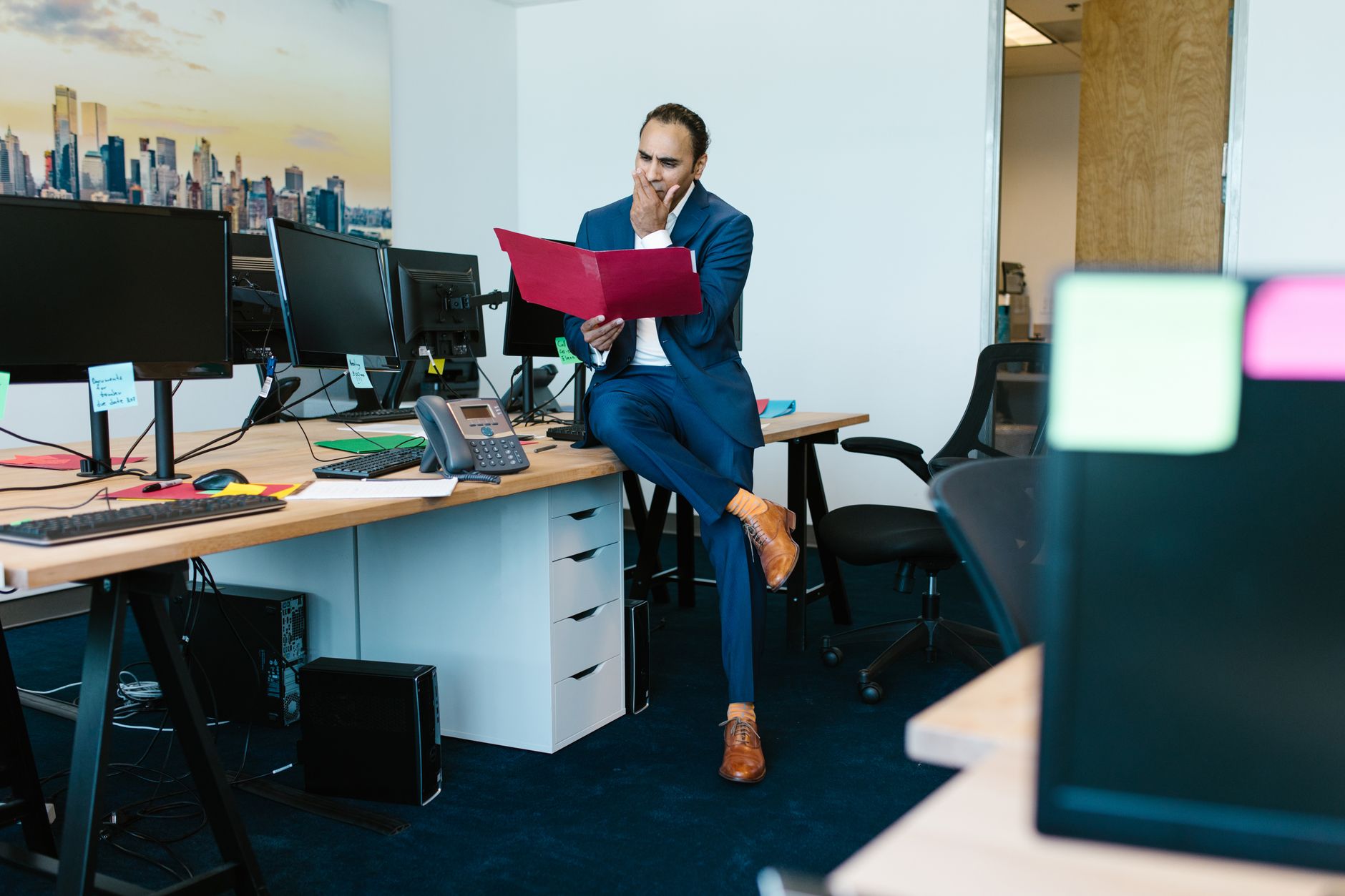 A thoughtful businessman examines documents in a modern office setting.